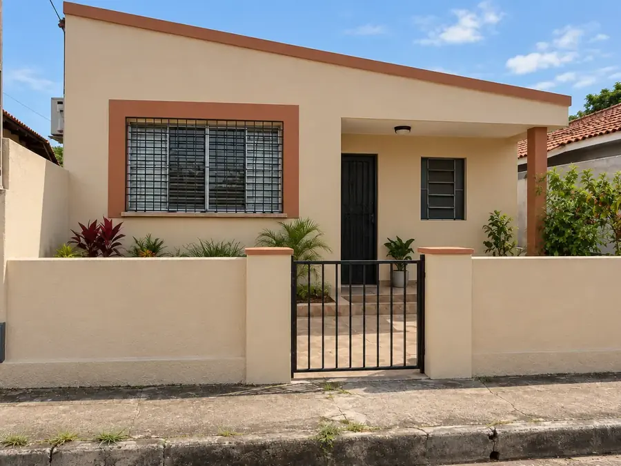 Frente de casa com reboco novo na cor areia e portão preto