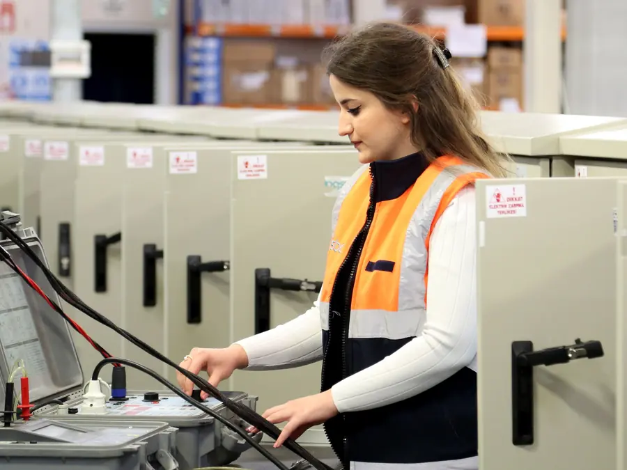 Josiane Moreira, eletricista, de colete laranja, testando equipamentos elétricos