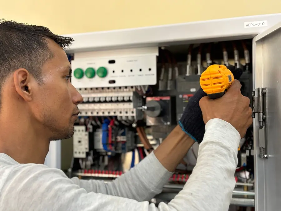 Sérgio Andrade, eletricista, montando disjuntores em um quadro de distribuição com furadeira
